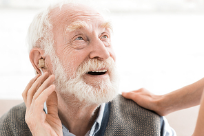 Glad man with hearing aid in ear, looking away