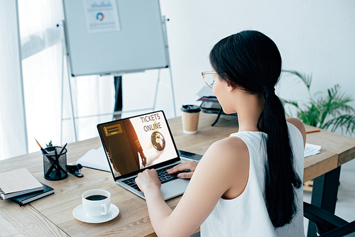 young latin businesswoman using laptop with tickets online website on screen