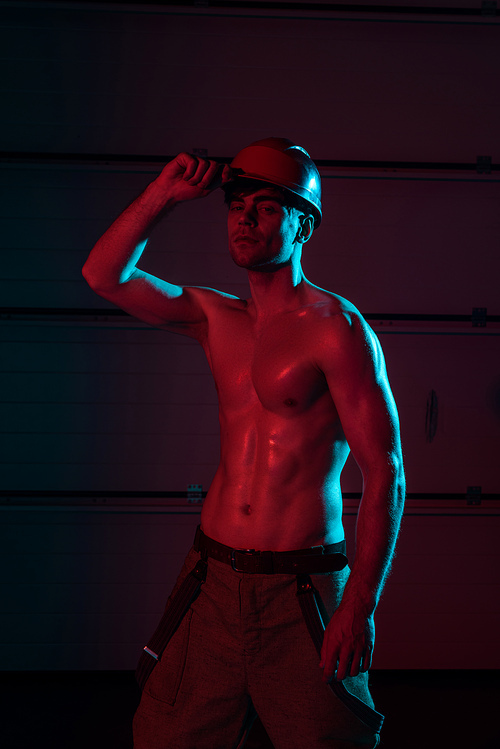 sexy shirtless fireman in protective hardhat in darkness