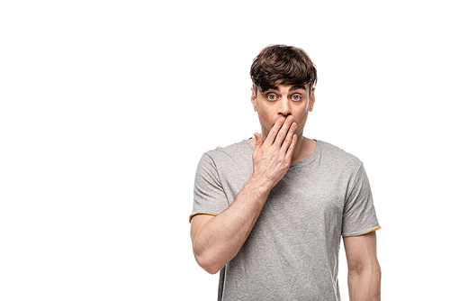 shocked young man  while covering mouth with hand isolated on white