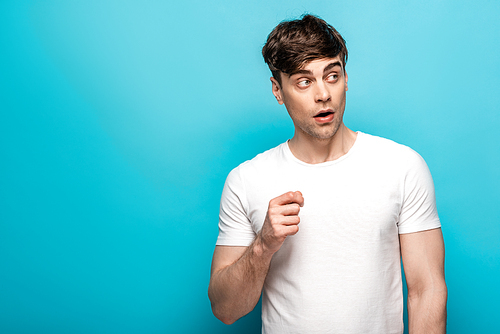 thoughtful young man in white t-shirt looking away on blue background