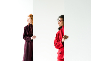 attractive redhead girl and african american woman standing on white