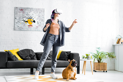 girl with colorful hair and VR headset standing near dog in living room