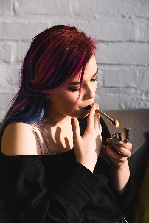 beautiful hipster girl lighting up and smoking joint with medical marijuana