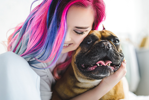 cheerful girl with colorful hair hugging cute bulldog