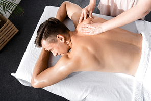 cropped view of masseur and shirtless man lying on massage table