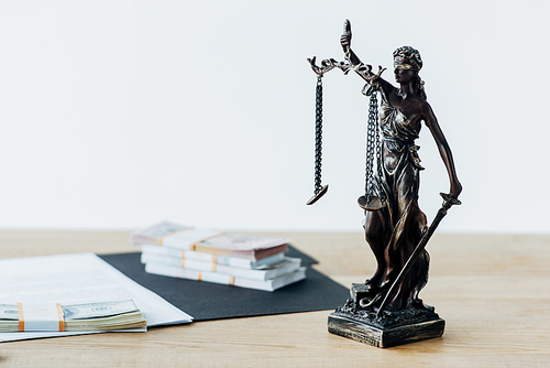 selective focus of money on folder with documents near statuette of justice