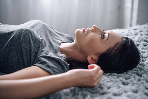 beautiful depressed woman lying on bed at home