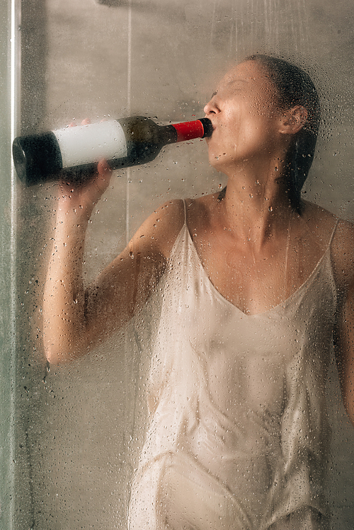 lonely depressed woman in shower drinking wine at home