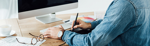 Cropped view of ux developer using graphics tablet and computer near sketches on table, panoramic shot