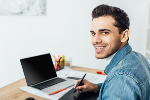 Smiling ux designer  while using graphics tablet and laptop at table