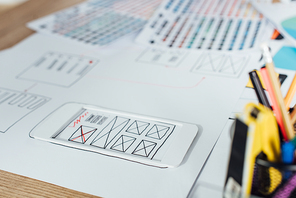 Selective focus of layouts of user experience design sketches and stationery on table