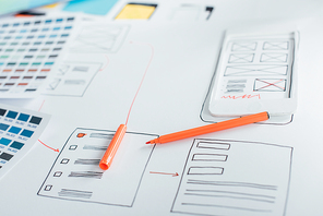 Selective focus of marker on sketches of website design near color palettes on table