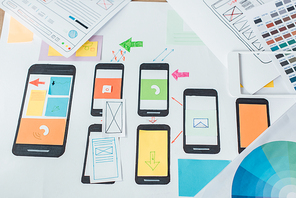 Top view of color circle and sketches of mobile user experience design on wooden table