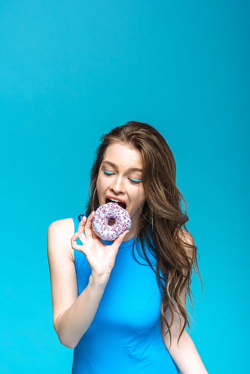 pretty girl in swimsuit eating donut isolated on blue