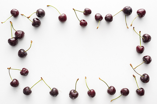 top view of sweet and fresh cherries covered with water drops on white background