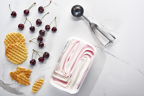 top view of waffles, spoon and cherries and ice cream on marble grey background