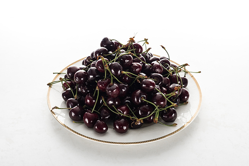 ripe, fresh and sweet cherries on plate on white background