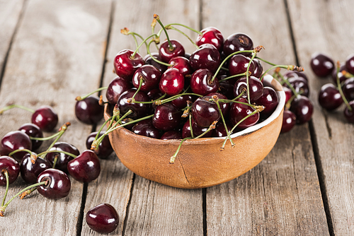 red, fresh, whole and ripe cherries on bowl on wooden surface