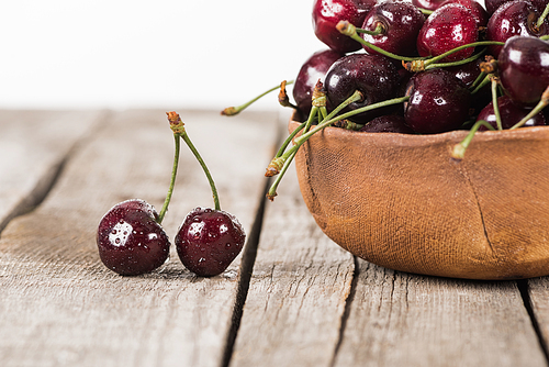 red, fresh, whole and washed cherries on bowl on wooden table