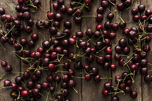 top view of red, fresh, whole and washed cherries on wooden surface