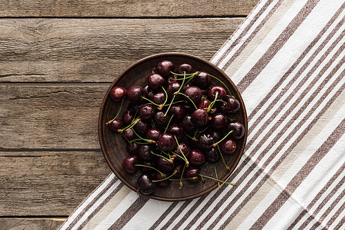 top view of fresh, whole and ripe cherries covered with water drops on plate