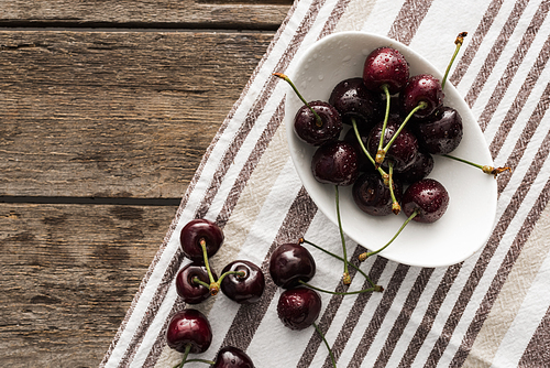 top view of fresh, whole and ripe cherries covered with water drops on bowl