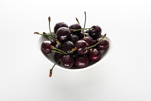 red, whole and ripe cherries covered with water drops on bowl