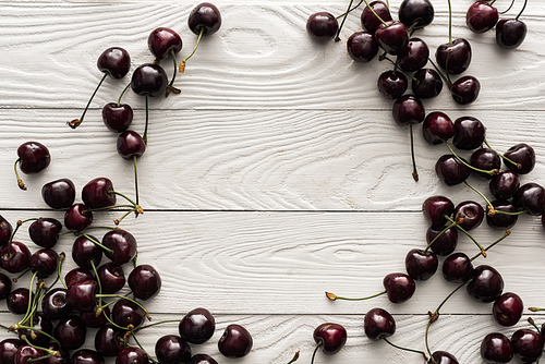 top view of fresh, sweet and ripe cherries on wooden background