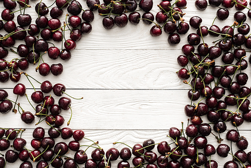top view of fresh, sweet and ripe cherries covered with droplets on wooden background