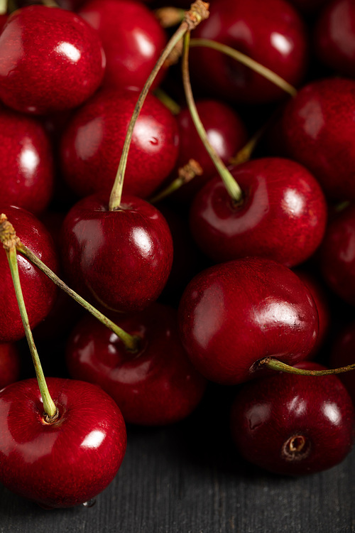 close up view of red delicious shiny cherries on wooden table