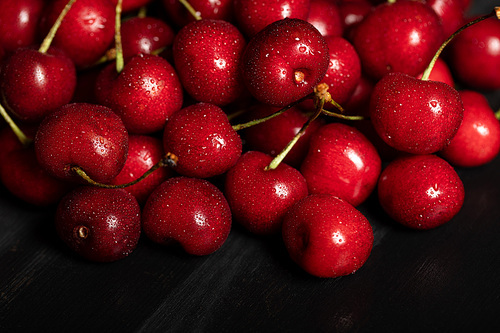 red delicious and ripe cherries with water drops on black cloth