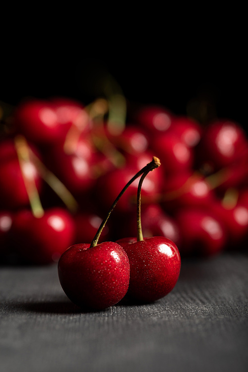 selective focus of red delicious sweet cherries on wooden table isolated on black