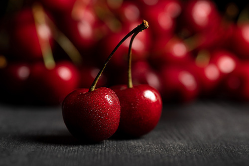 selective focus of red delicious sweet cherries on wooden table