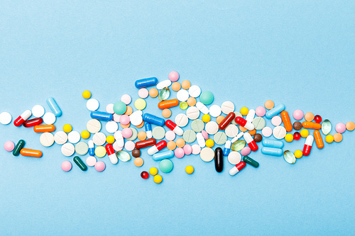 Top view of colorful pills on blue surface