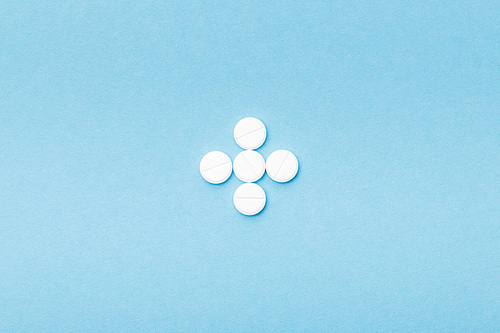 Flat lay with white pills on blue surface
