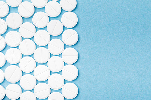 Top view of white pills on blue surface