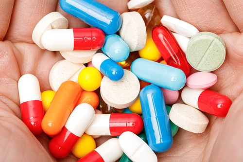 Partial view of woman holding colorful pills in hands