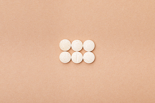 Top view of white pills on brown surface