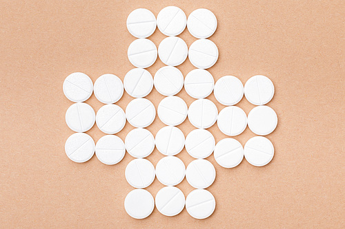Flat lay with white pills on brown surface