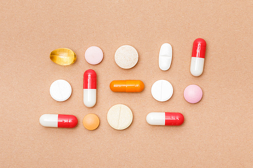 Top view of colorful pills on brown surface