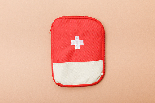 Top view of red first aid kit bag on brown surface