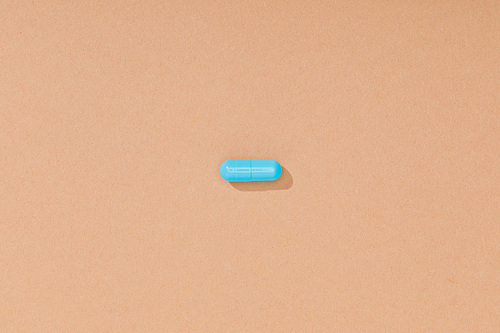 Top view of blue pill on brown surface