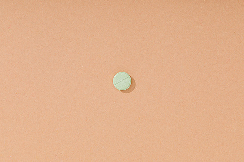 Top view of green pill on brown surface
