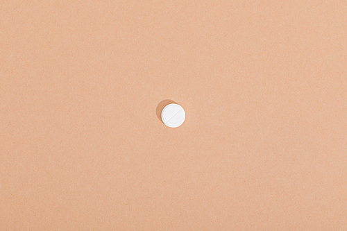 Top view of white pill on brown surface