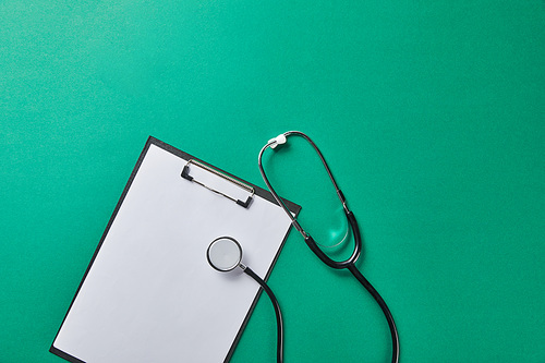 top view of stethoscope near folder with blank paper isolated on green