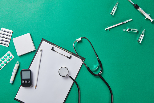 top view of various medical supplies near folder and stethoscope on green surface