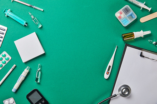 top view of various medical supplies with empty space in middle on green surface