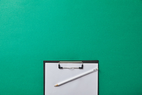 top view of pencil on folder with blank paper isolated on green