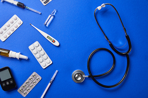 top view of stethoscope near various medical supplies on blue background